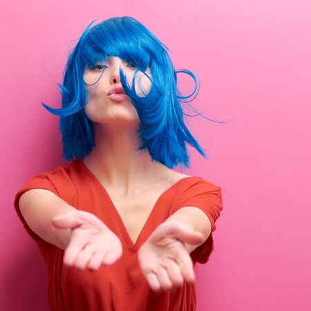 studio portrait of a sexy beautiful girl with a smile in motion on a pink background. Girl with blue hairの写真素材