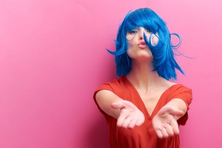 studio portrait of a sexy beautiful girl with a smile in motion on a pink background. Girl with blue hairの写真素材