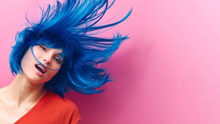 studio portrait of a sexy beautiful girl with a smile in motion on a pink background. Girl with blue hairの写真素材