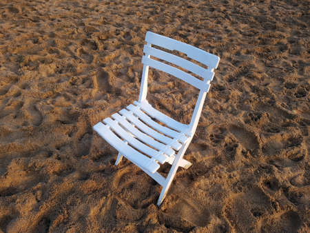 an empty white plastic chair on the beach sand, holiday concept background.の写真素材