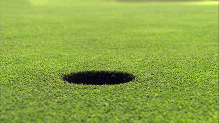 A hole on the golf course in close up view with green grass ground background.の写真素材