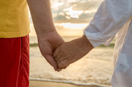 Senior man and woman holding hands of each other at the beachの写真素材