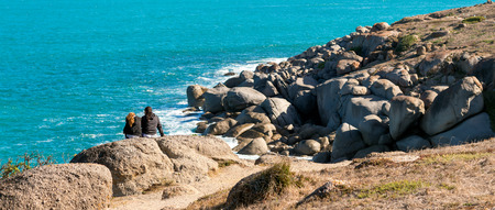 Two girls sitting on the rock of Granite Island, Victor Harbor. Warm tonesの写真素材