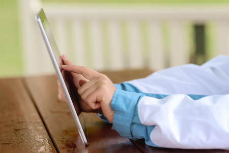 Woman sitting at a table and holding a tabletの写真素材