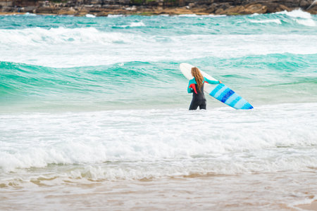 Sydney, Australia - November 8, 2015: Surfer girl entering the waters of Bondi Beach. Bondi beach is one of the most famous places for surfing in Australiaのeditorial素材