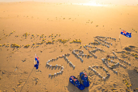 Straya text drawn using shells on sand with flags and thongs. Straya is an abbreviation of Australiaの写真素材