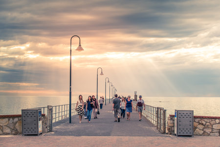 Adelaide, Australia - January 19, 2016: People walk along Glenelg Jetty at sunset. Jetty was opened for public on 25 April 1859 and is one of the most popular tourists attractionsのeditorial素材