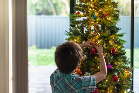 Boy decorating a Christmas tree, South Australia. Focus on handsの写真素材