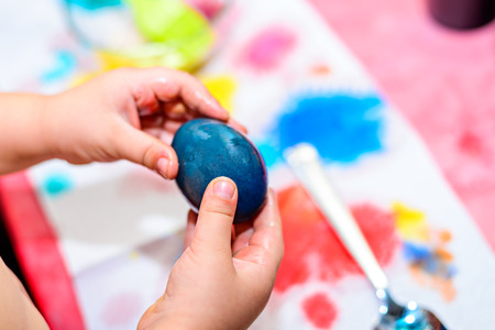 Child holding freshly colored Easter egg in his handsの写真素材