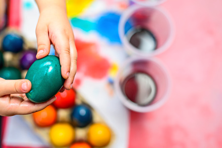 Child holding freshly colored Easter egg in his handsの写真素材