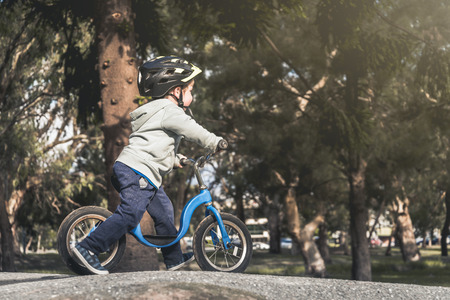 Australian kid riding his balance bike and wearing helmet in the park, South Australiaの写真素材