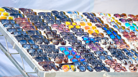 Colorful variety of cheap sunglasses displayed on market stall for saleの写真素材