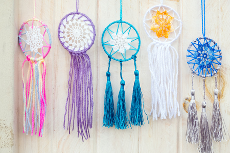 Colorful handmade dream catchers hanging on the white wooden wallの写真素材