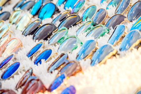 Colorful variety of cheap sunglasses displayed on market stall for saleの写真素材