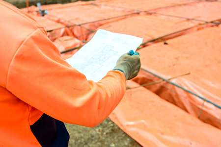 Builder checking plan for steel fixing  of new Australian suburban house. Focus on hand
