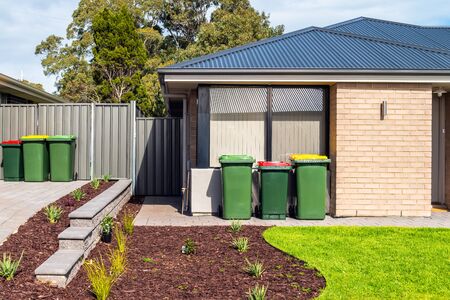 Australian wheelie bins with colourful lids for organic, general waste, and recycling products provided by local city councilの写真素材