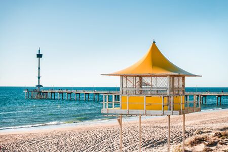Brighton surf life saving tower with people walking along the jetty on the background, South Australiaの写真素材