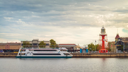 Port Adelaide, Australia - December 8, 2018: Iconic Port Adelaide lighthouse with Dolphin Explorer boat viewed across Port River at sunsetのeditorial素材