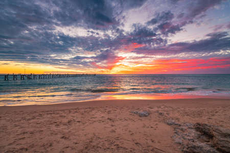 Port Noarlunga beach foreshore with people on the pier and dramatic sunset on the backgroundの写真素材