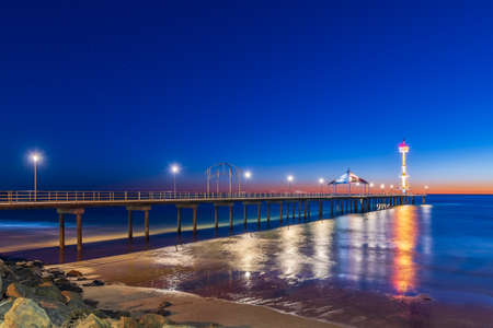 Iconic Brighton beach foreshore with jetty illuminated at dusk, South Australiaの写真素材