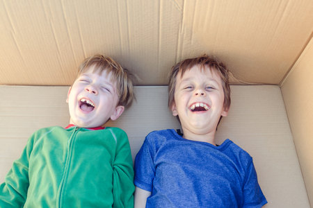 Cheerful boys having fun inside a big carton boxの写真素材