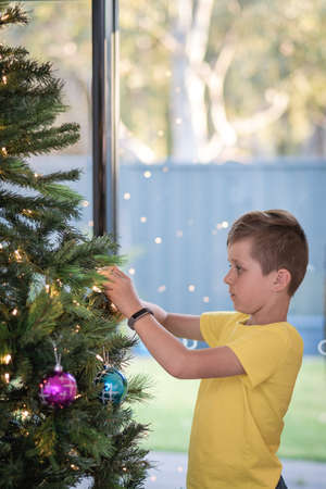 Portrait of a boy decorating Christmas tree at home in South Australiaの写真素材