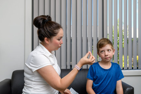 Mother going to do the COVID-19 rapid antigen test for her son by showing him a swab