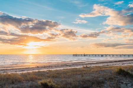 Glenelg Beach with jetty and people silhouettes in the background at sunset, South Australiaの写真素材