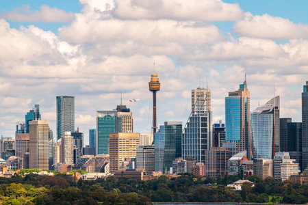 Sydney city skyline panorama with a plane taking off above while viewed across the harbour from Bradleys Head on a bright dayの写真素材