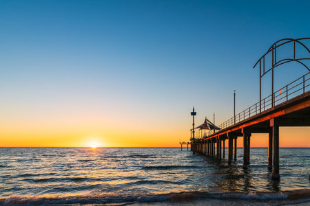 Brighton Jetty with sea views from beach as sun drops behind horizon on summer eveningの写真素材