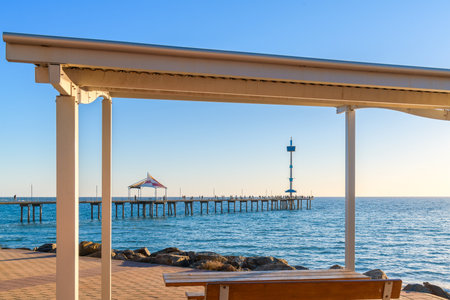 Brighton Jetty with people viewed from Esplanade through picnic gazebo on a bright day, Adelaide, South Australiaの写真素材