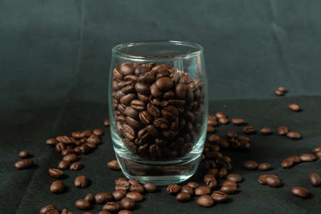 Dark roasted coffee beans with glass on black backgroundの写真素材
