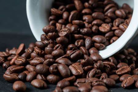 Dark roasted coffee beans with glass on black backgroundの写真素材