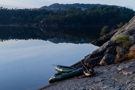 Two packrafts resting on rock besides a lake.の写真素材