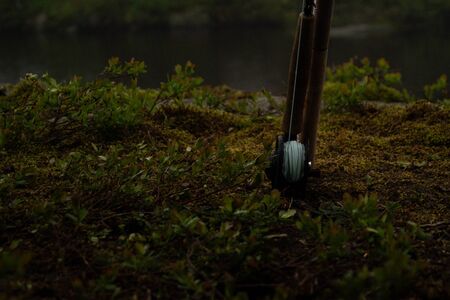 Flyfishing rod, resting in grass with lake in backgroundの写真素材