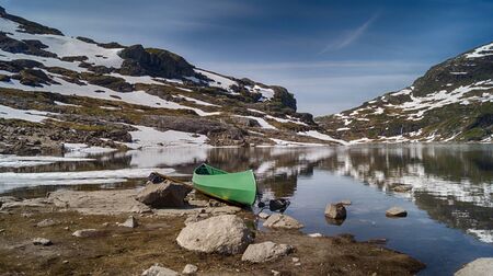 Canoe in a mountain lake with snowy hillsidesの写真素材