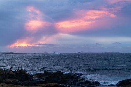 Sunset with waves hitting rocks on the shore line, clouds in the skyの写真素材