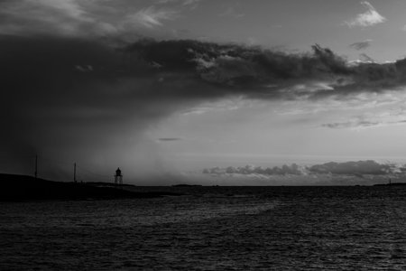Lighthouse by the sea with bad weather coming in, dramatic clouds.