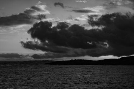 Dramatic clouds with ocean and coastline, black and white imageの写真素材