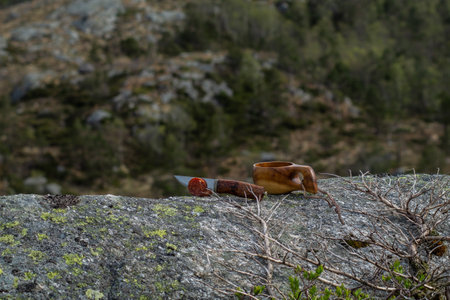 Knife and sausage in the mountain with blurry mountain landscape in background, with coffee cupの写真素材