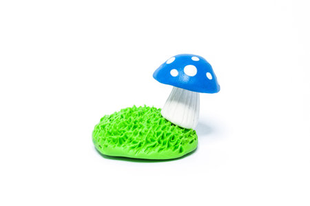 Mushrooms Blue plasticine crafts on green grass on a white background.の写真素材