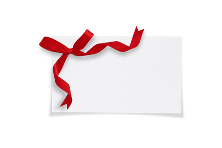 White paper card with a red bow on a white background.の写真素材