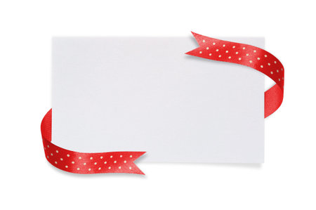 White paper card with a red ribbon bow on a white background.の写真素材