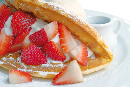 Strawberry waffles and honey on a white plate on a white background.の写真素材