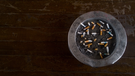 Bangkok,Thailand-Apil 10,2017:Cigarette butt cigarette on Ashtray with sand and cigarette stubs outdoors on wood background.Concept for World No Tobacco Day.のeditorial素材