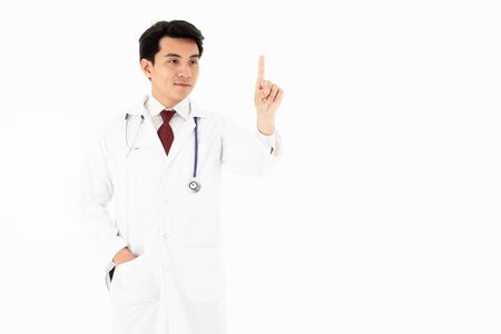Portrait of the handsome young man doctor has a stethoscope on the neck. He points and looks the finger on white background, isolated.の写真素材
