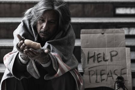 Homeless people living in various cities He waited and needed help from the kind people to give him all the necessary things, clothing, bread, water, and home. He is dirty and has no money with him.の素材 [FY310134453742]