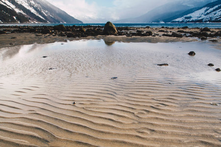 Rippling Sand Patterns on Beach in Alaska with Distant Waves on Rocky Shoreの写真素材