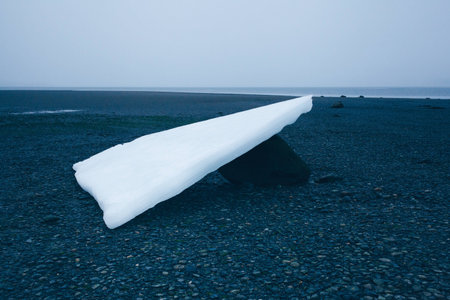 Ice on Distant Alaska Shore Revealed at Low Tide Resting on Large Boulderの写真素材