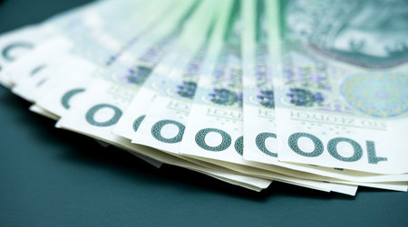 'Close-up of a stack of one hundred Polish zloty banknotes on a dark surface, highlighting the...